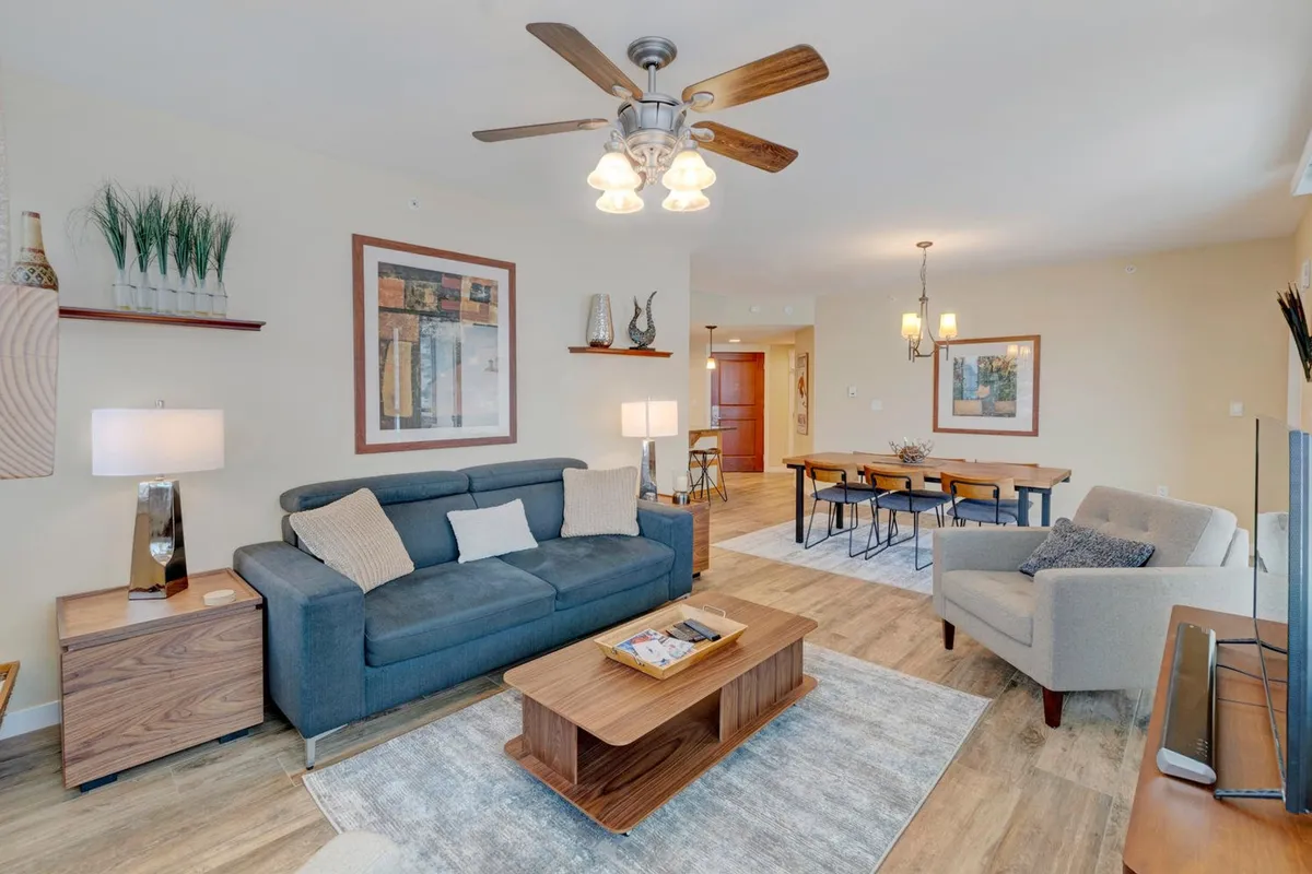 A view of the cozy living and dining area, with a sofa, coffee table, and visible dining space. The atmosphere is warm and welcoming, showcasing the adjacent dining area that makes every meal inviting and family-friendly.