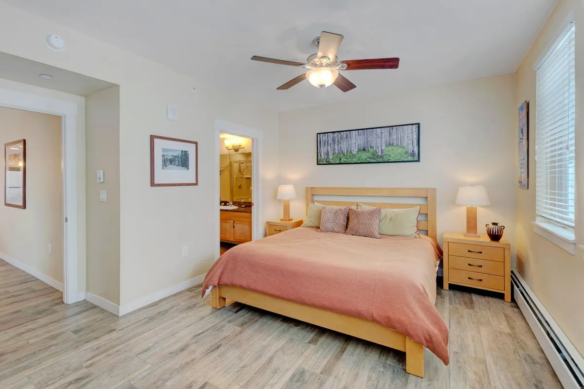 A restful bedroom with a cozy bed, matching nightstands, tasteful artwork, and a window that offers a glimpse outside, creating an inviting and calm atmosphere.